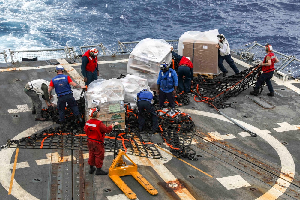 U.S. Navy sailors receiving palletised supplies and handling cargo nets on the deck of USS Shoup at sea